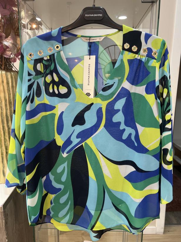 Blusa com tons de verde e de azul, com decote em v e com ilhoses